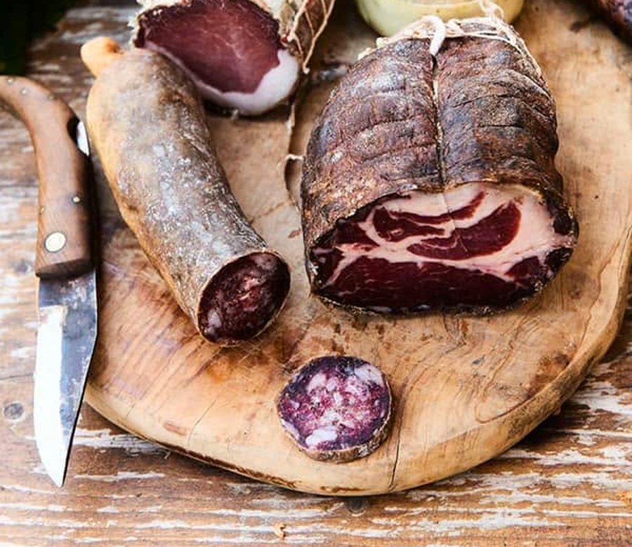 Coppa, salsiccia et figatellu sur une planche d’olivier, avec un couteau de berger